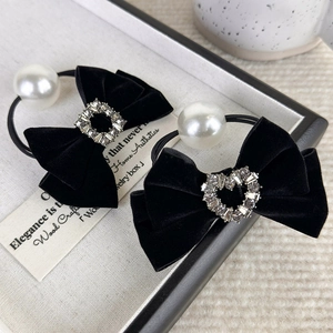 Detailed macro view of two black velvet bow hair ties with pearl and rhinestone accents