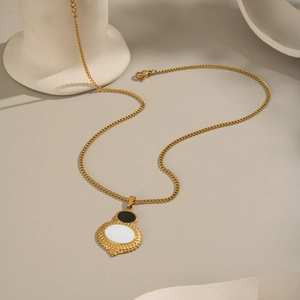 Dettaglio della collana geometrica dorata con pietre preziose ovali in bianco e nero