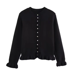 Détail du cardigan noir en maille avec boutons en perles et bordures à volants