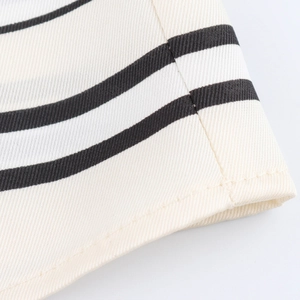 Detailed close-up of cream satin shirt sleeve with black horizontal stripes and twill texture