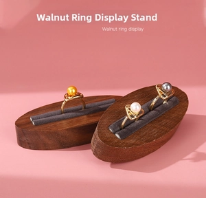Macro shot of walnut wood ring display with gray velvet slots and pearl rings