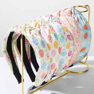 Detail of five fabric Easter headbands with egg and bunny prints on a golden display stand
