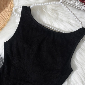 Close-up of black lace fabric texture and floral embroidery detail on a jumpsuit