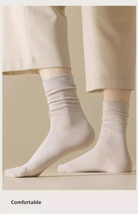 Detail of beige cotton slouch socks with fine ribbed texture for women in minimalist style