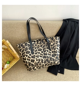 Close-up of leopard print tote bag with black leather handles on a beige sofa