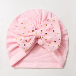 Detail of pink baby turban hat with golden polka dot bow and soft elastic fabric