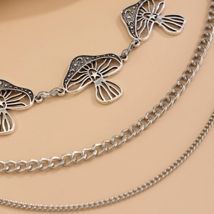Macro detail of triple-layer vintage silver body chain with engraved mushroom charms