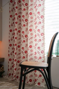 Detail of Christmas curtain with red candy print and decorative beige tassels