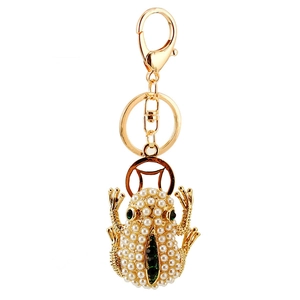 Golden frog keychain with white pearl pavé body and green stripe on white background