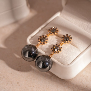 Détail de boucles d'oreilles vintage en or avec tournesols gris et perles gris foncé