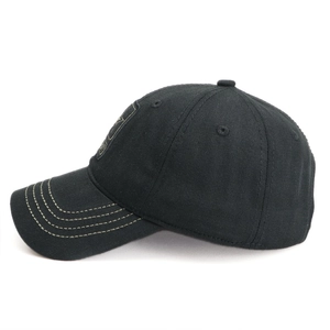 Detail of black baseball cap with shield star embroidery and yellow stitching accents
