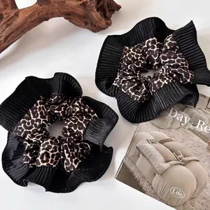 Satin leopard print scrunchie with pleated black trim and soft texture on magazines