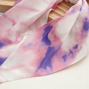Detailed close-up of soft pink and purple tie-dye fabric texture on a scrunchie scarf