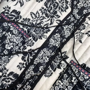 Detail of quilted floral jacket featuring intricate embroidery and black ribbon ties