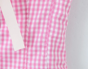Macro shot of pink gingham fabric with fine stitching and white ribbed ribbon details