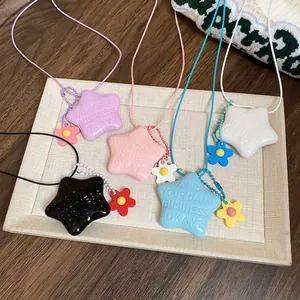 Set di collane a stella con ciondoli in resina colorata e piccoli dettagli floreali su vassoio