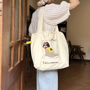 Detailed embroidery of dog and slogan on cream canvas tote bag with pleated closure