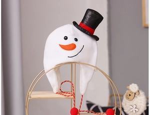 Detail of plush white snowman hat with black top hat and festive red pom-poms