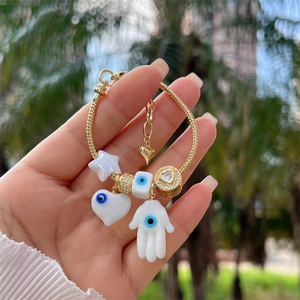 Detail of 18K gold-plated snake chain with Hamsa and Evil Eye charms on wrist