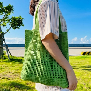 Close-up of grass green hollow-out knitted tote bag on model for summer casual wear