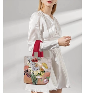 Detail of oil painting floral bucket bag with red handle carried by model in white dress