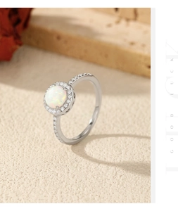 Detail of silver S925 ring featuring a round white opal center with halo stones