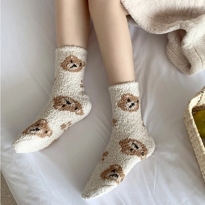 Close-up of cozy coral fleece socks with cute brown bear pattern for winter warmth