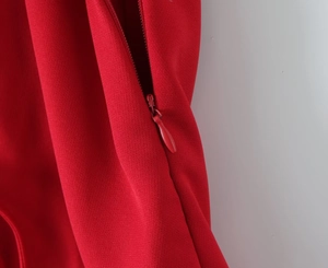 Close-up of a concealed back zipper on a red tiered dress with fine fabric texture