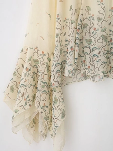 Détail de l'imprimé floral sur mousseline beige plissée avec ourlet ondulé et texture