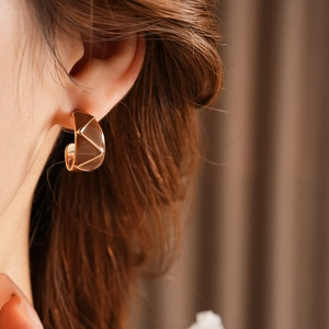 Close-up of vintage enamel C-shaped earrings in rose gold finish on model's ear