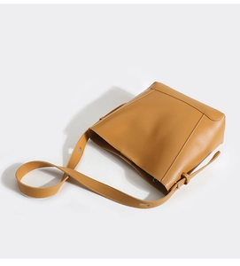 Close-up of brown faux leather bucket bag showing the wide main compartment and strap