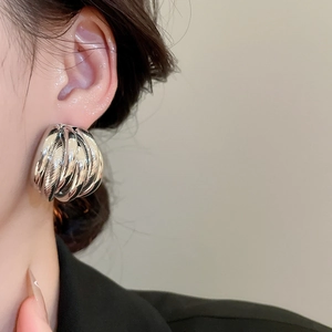 Macro close-up of chunky layered spiral stud earrings in a glossy silver finish