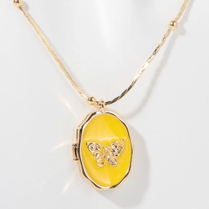 Makroansicht einer goldenen ovalen Medaillon-Halskette mit Schmetterling auf weißem Grund