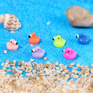 Close-up of 6 colorful resin flamingo miniatures on blue sand for DIY landscaping