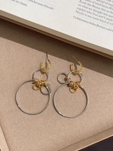 Détail de boucles d'oreilles géométriques dorées et argentées sur plateau chic