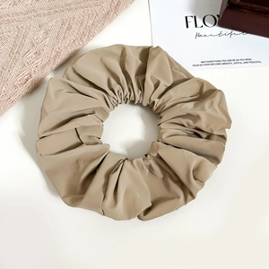 Close-up of khaki faux leather scrunchie with pleated texture and soft glossy finish