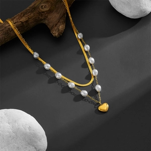 Double-layer gold heart necklace with pearls and engraved love charm on a stone base