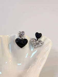 Detail showing asymmetrical heart earrings with hammered metal texture on shell tray