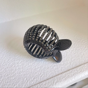 Detailed close-up of a black circular hair claw clip with sparkling rhinestones decoration