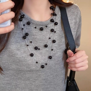Three-layer long pearl necklace with black beads and silver chain on female model