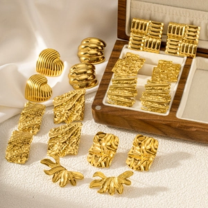 Collection of geometric 18K gold-plated stainless steel earrings on white silk surface