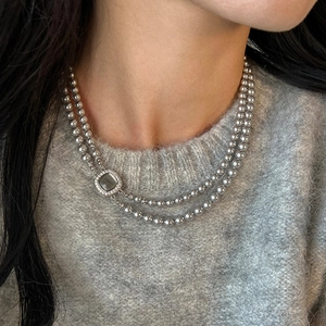 Detail of double-layer grey pearl necklace with square zircon pendant on sweater