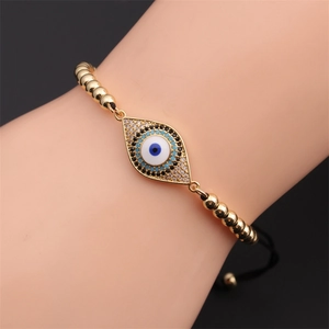 Adjustable gold bead bracelet featuring zircon-studded evil eye charms worn on wrist
