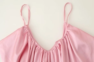 Dettaglio dell'abito sottoveste in raso rosa con scollo a V a pieghe e spalline sottili