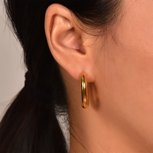 Close-up of chunky 18K gold plated stainless steel U-shaped hoop earrings on model