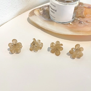 Set of four small amber resin flower hair claws on a clean white surface with pearls