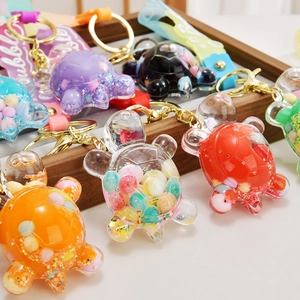 Detail of colorful liquid quicksand turtle keychains with glitter and bubble strap