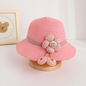 Detailed view of pink woven straw sun hat with floral decoration and soft grey ribbon
