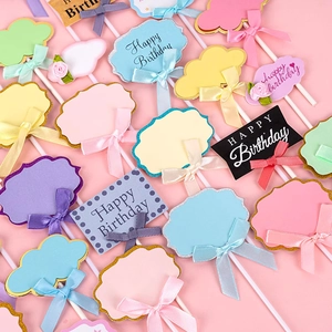 Pastel DIY writable birthday cake toppers with colorful ribbon bows and floral accents