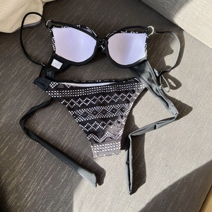 Close-up of black underwire bikini top with silver metal rings and white padded cups
